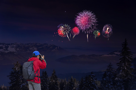 Woman enjoying fireworks celebration and taking photos on the mountain.