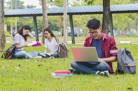 Group of university asian students having fun outdoors,Man using laptop computer at university high school campus,college in summer holiday relaxation.の写真素材