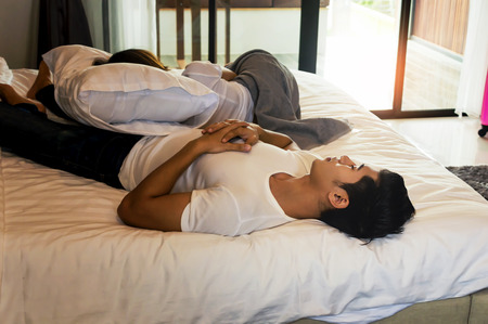 Asian couple traveler tried to travel vacation together and sleep on the white bed.Travel concept.の写真素材