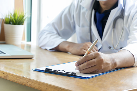 Stethoscope with clipboard and Laptop on desk,Doctor working in hospital writing a prescription, Healthcare and medical concept,test results in backgroundの写真素材