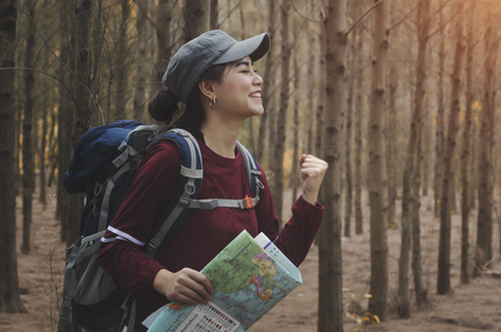 Hipster tourist with backpack enjoying sunset on trip, lifestyle concept adventure, traveler with backpack on background forest landscape horizon, young girl hiker pointing hands on trekking plan.の写真素材