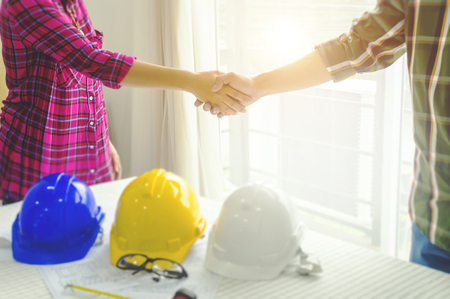 Asian construction engineer joining hands with architect after finish meeting about develop a plan house at construction site, business colleagues teamwork conceptの写真素材