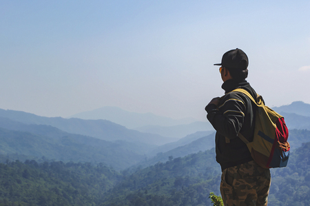 Young man hiker with backpack standing on top of a mountain.の写真素材