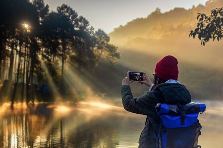 Beautiful woman travel morning sunrise and tourist camping on the lake with foggy in the morning,Pang Ung, Mea Hong Son,North of Thailand.の写真素材