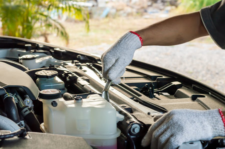 Close up hands of unrecognizable mechanic doing car service and maintenance. Car mechanic man at the garage fixing the engine. Hands of car mechanic with wrench. Auto Service Business Concept.の写真素材