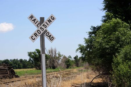 a railroad crossing sign by the tracksの写真素材