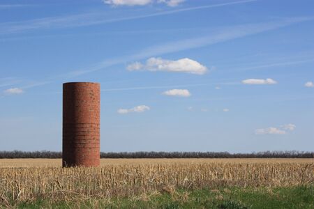 A red silo in the middle of a field with bluesky.の写真素材