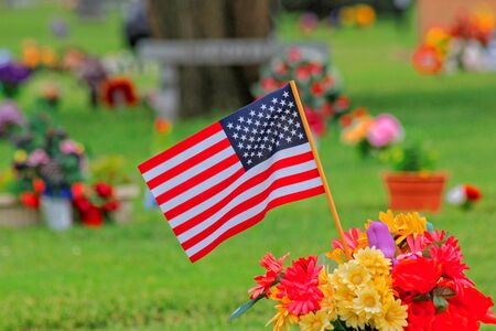 A US Flag on Memorial Day in a cemetery with flower s and green grass shot in Kansas の写真素材