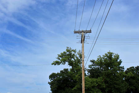 A shot of Power Lines on a pole with blue sky and green tree's in Sterling Kansas USA.
