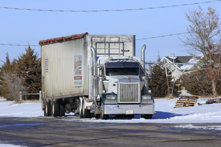A shot of a Diesel Tractor trailer in a street in Greensburg Kansas USA with snow and blue sky in the winter time that's bright and colorful.のeditorial素材