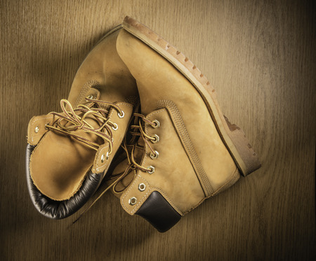 Pair of old yellow working boots Isolated on wood background