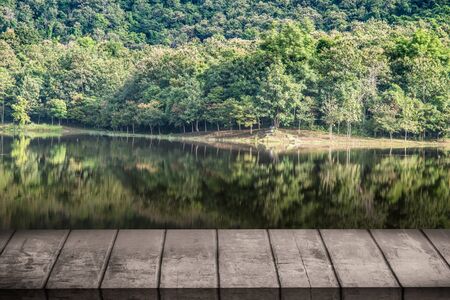 vintage wooden board table in front of dreamy and abstract forest landscape lagoon