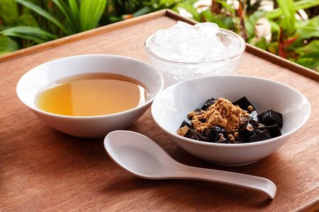 Grass jelly dessert  herbal gelatin , syrup, ice, and brown sugar on the wooden background. Chinese style.の写真素材