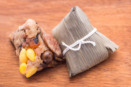 Two Zongzi or Asian Chinese sticky rice dumplings on wooden background. Zongzi is a traditional Chinese food eaten during the dragon boat festival.の写真素材