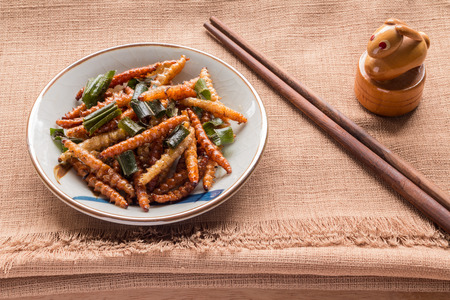 Fried insects - Wood worm insect crispy with pandan after fried and add a light coating of sauce and garnish Thai pepper powder and chopsticks on brown cloth background, select focusの写真素材