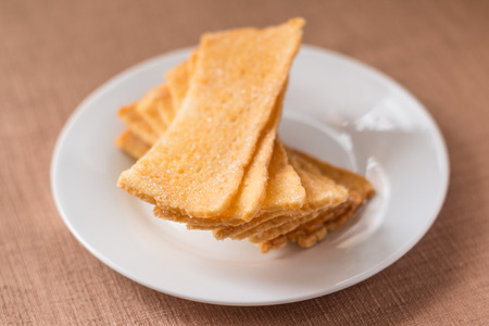 Sliced crispy bread in white ceramic dish on brown tablecloth background.の写真素材