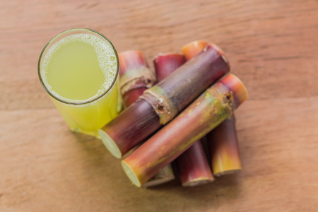Sugarcane juice with piece of sugarcane on wooden background. Top view.の写真素材