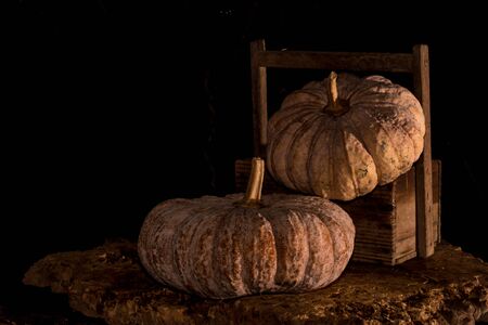 Pumpkins with dark background - Traditional pumpkins and wooden crate on rustic old wooden boards with dark backgroundの写真素材