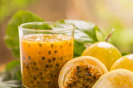 Passion fruit - Passion fruits half and juice with leaves on the vintage wooden background. Closeup,...