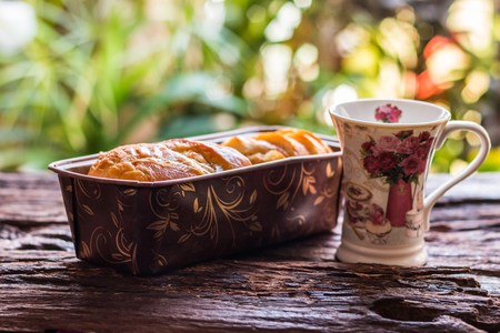 Sliced bread - Homemade bread and slices of bread in a brown cardboard box rustic and cup of coffee on old wooden table background. Select focus.の写真素材