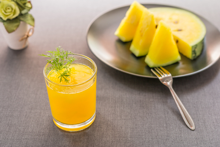 Watermelon juice with yellow pulp and fresh sliced of watermelon on black plate with gray tablecloth background. Select focus.の写真素材