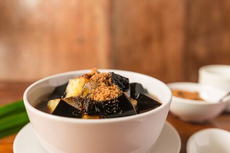 Grass jelly dessert herbal gelatin or jelly black with pineapple, syrup, ice, and brown sugar on the...