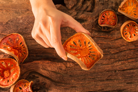 Dried Bael fruit organic herb for Skin, Hair, and Health in girl's hands on a rustic wooden backgroundの写真素材