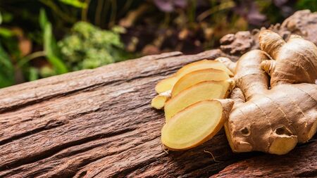Ginger root - Fresh ginger root and sliced on old plank with nature background. Close-up, Selective focusの写真素材