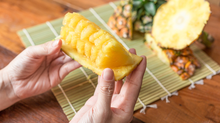 Pineapple with slices - Human female hands holding pineapple slices. Tropical fruit concept. Close-up, Selective focus.の写真素材