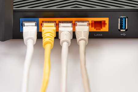 Wireless internet router with connected cables, The backside of fiber optic internet, and network...