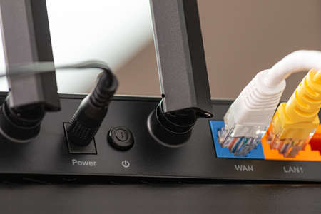 Wireless internet router with connected cables, The backside of fiber optic internet, and network...