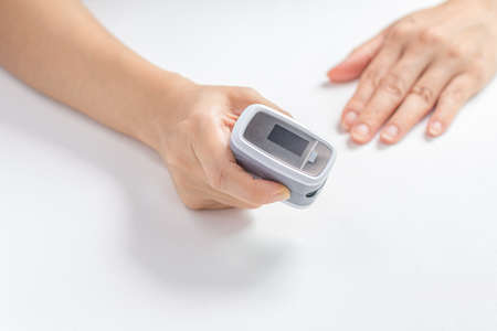 Female hands hold the Digital Pulse Oximeter for use with measures the patient's pulse and oxygen...