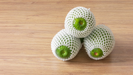 Green avocados with foam fruit net cover on wooden background with copy space for texts. Avocados...