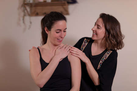 A woman therapist examines her patients shoulder