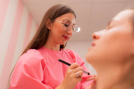 A beautician woman applying make-up to her client at the beauty salon