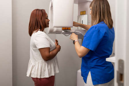 A dentist woman adjusts the x-rays machine at the dental clinic