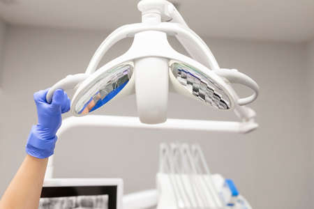 A dentist womans hand adjusting the dental chairs light at the dental clinicの写真素材