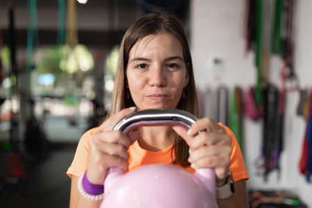 A young woman performs exercises holding the kettlebellの写真素材