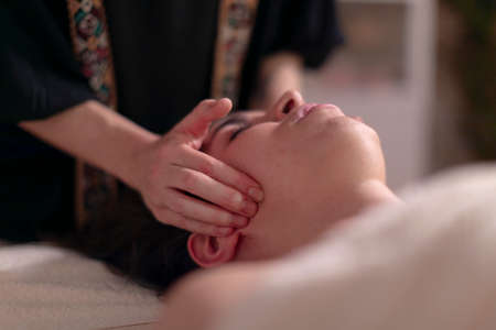 A masseuse massages the jaws of her patientの写真素材