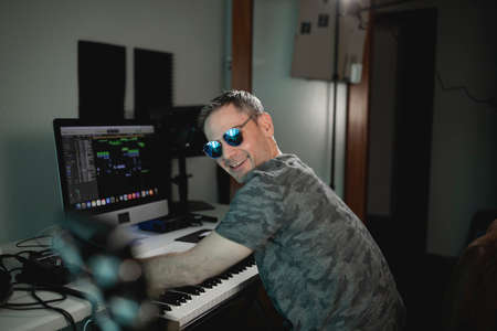 Music producer smiles at camera at his home studio