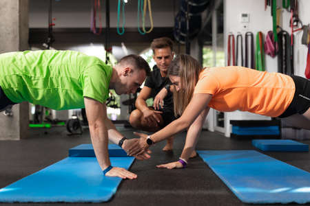 A couple of trainees giving high-fives as an exercise at the gym