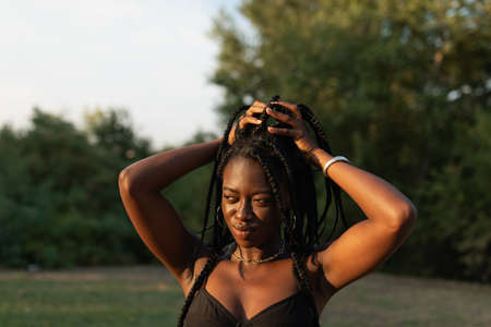 Portrait of a young black female holding her braids in a ponytail at the parkの写真素材
