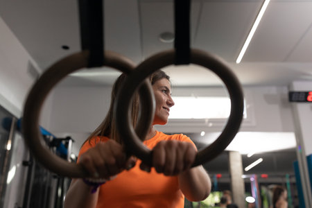 Portrait of a female trainee resting her hands on the rings at the gymの写真素材