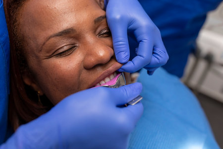 Close up view of a black woman patient being put on an impression tray inside her mouth