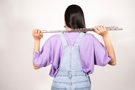 Back view of a young female flutist holding her instrumentの写真素材