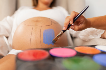 Close up view of an artist painting on a pregnant womans bellyの写真素材