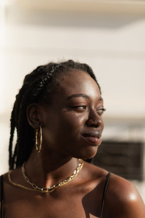 Close-up portrait of a young black female looking to the side in the streetの写真素材