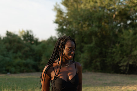 Young black female posing with style and looking down in the park during a photo shoot