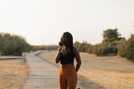 Young black female talking on the phone in the parkの写真素材