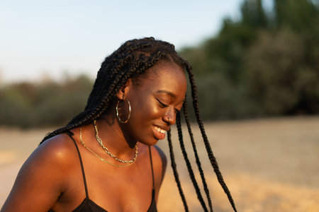 Close-up portrait of a young black female looking down while her braids move with inertia in the...